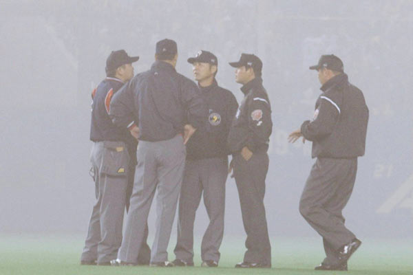 濃霧で視界不良になり協議する審判団(写真：時事)